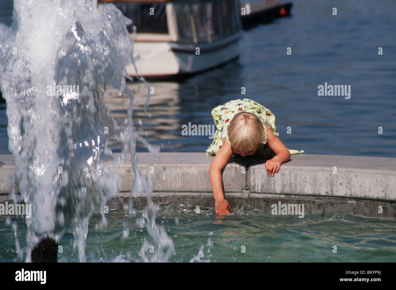 Toddler girl at risk while playing with fountain water outside Stock Photo