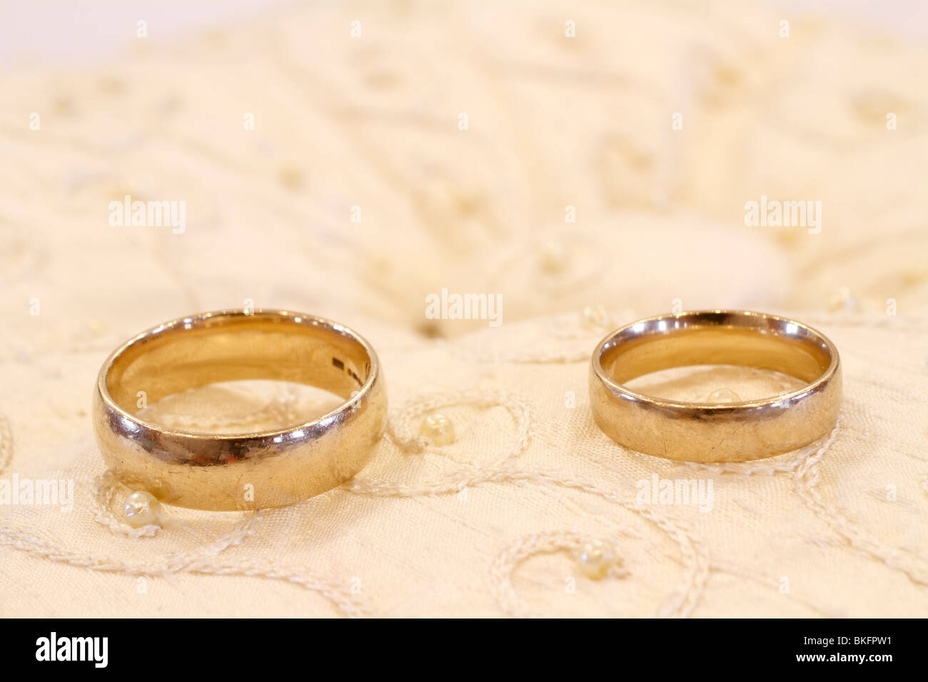 two golden wedding rings - his and hers, on a gold coloured presentation cushion ready for when needed during the wedding ceremony. Rufford wedding facilities, Rufford Mill Stock Photo