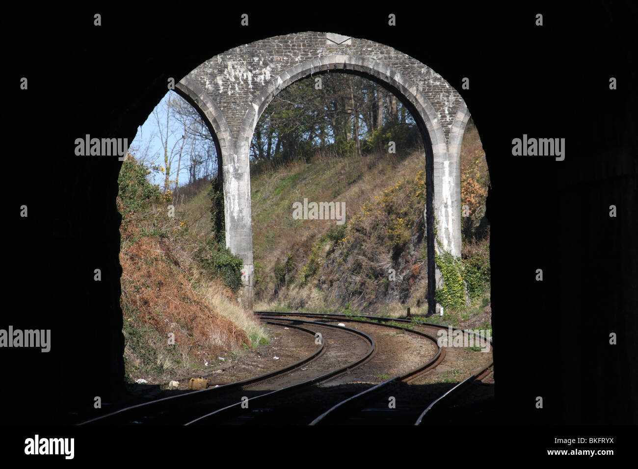 North West along the railway line from Conway (Conwy) station looking through a tunnel to the arches of a bridge. Stock Photo