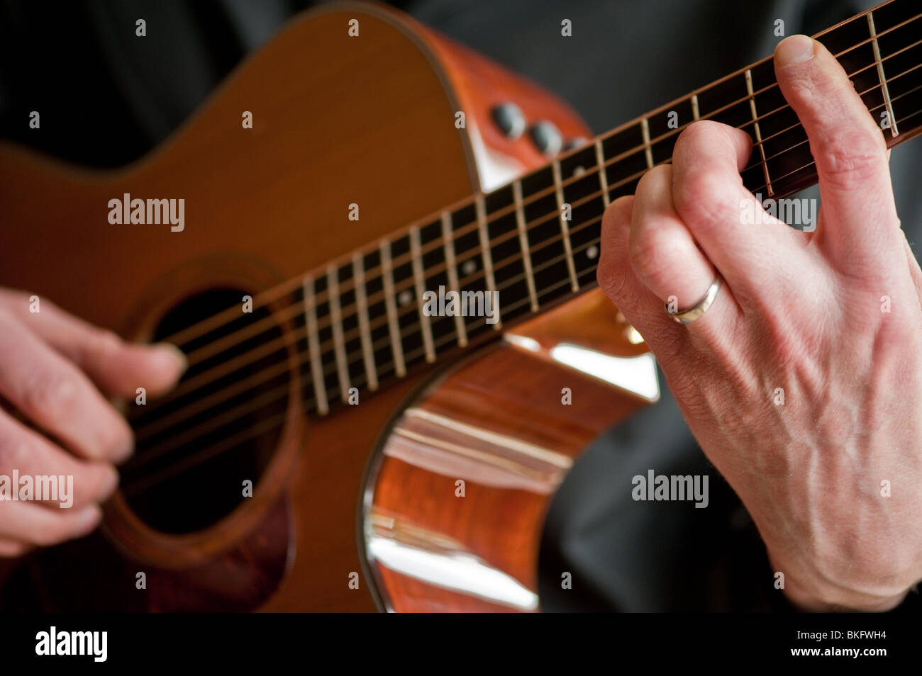 A close up view of hands playing a guitar Stock Photo