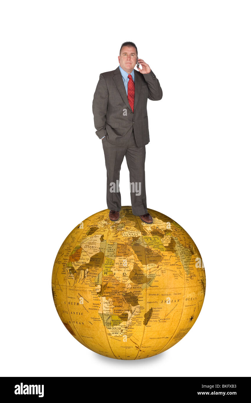 An international businessman standing on a world globe while talking on his cell phone. Stock Photo