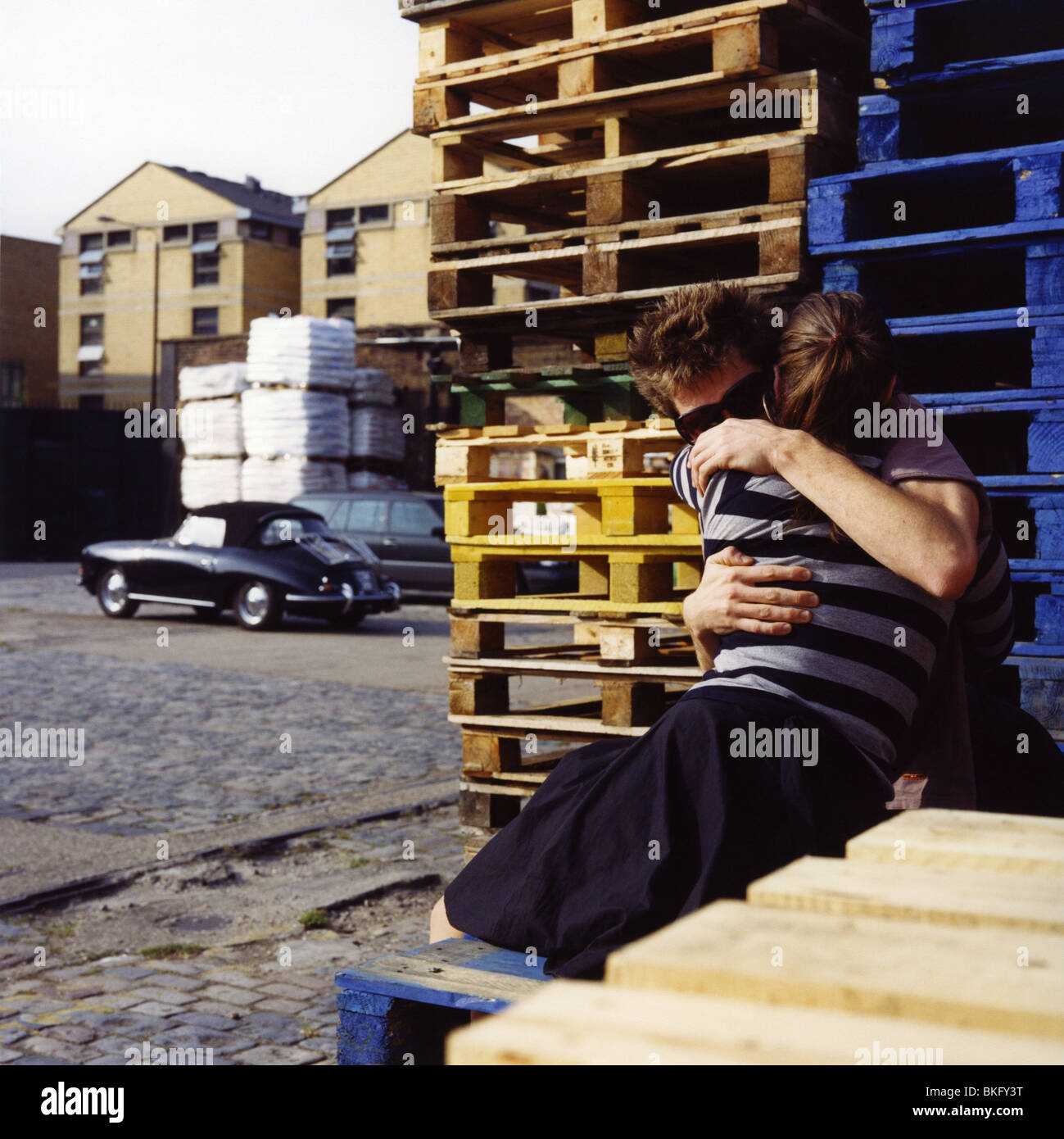 Hugging A Lod young couple hugging in parking lot with empty crates and a fancy ...