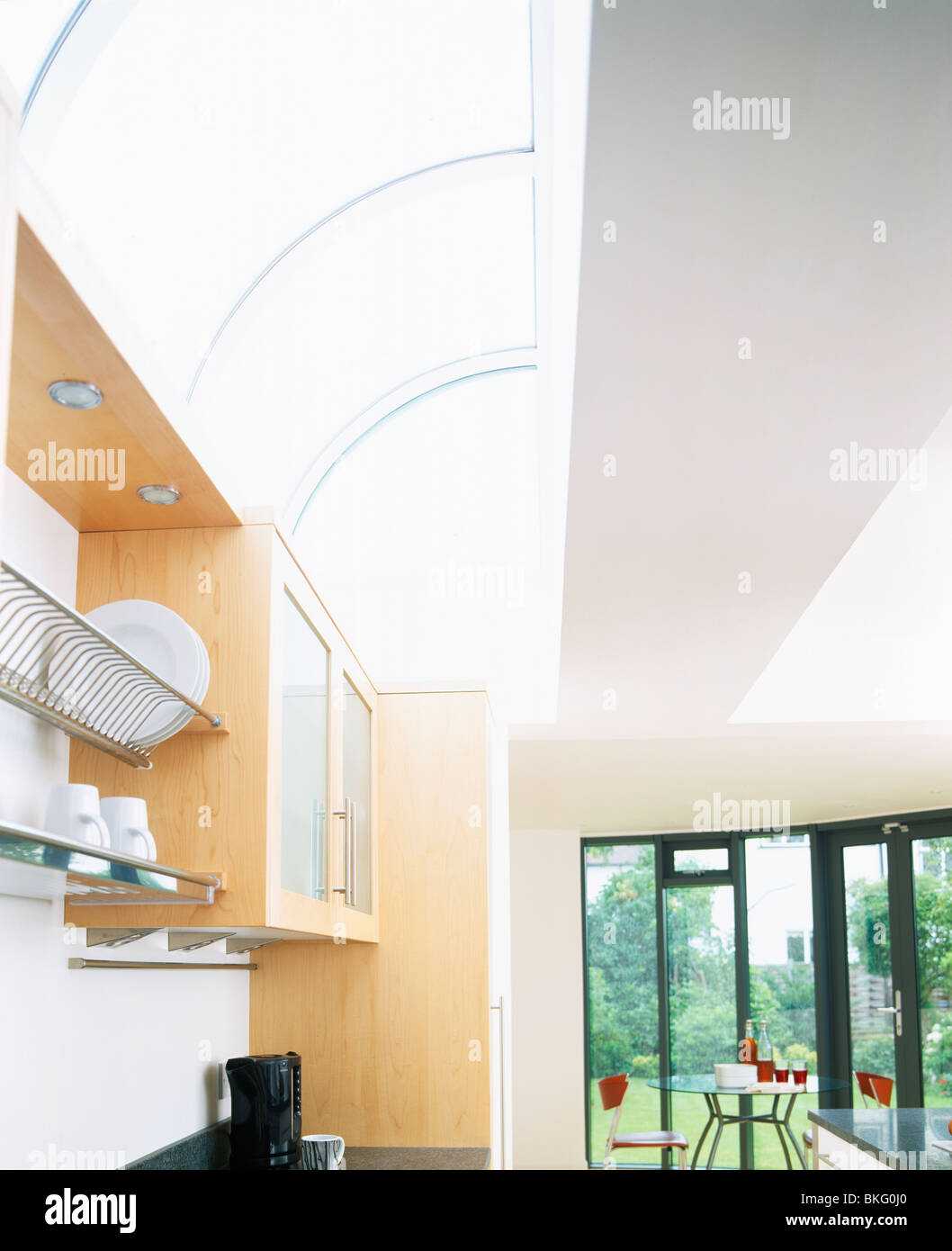 Curved glass ceiling in large modern kitchen with view of garden through patio doors Stock Photo