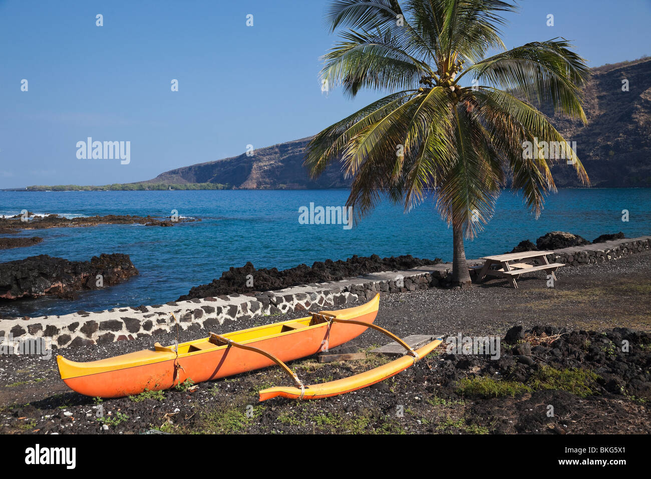 Outrigger canoe by  Kealakekua Bay in Hawaii  and Cook Monument in distance. Stock Photo