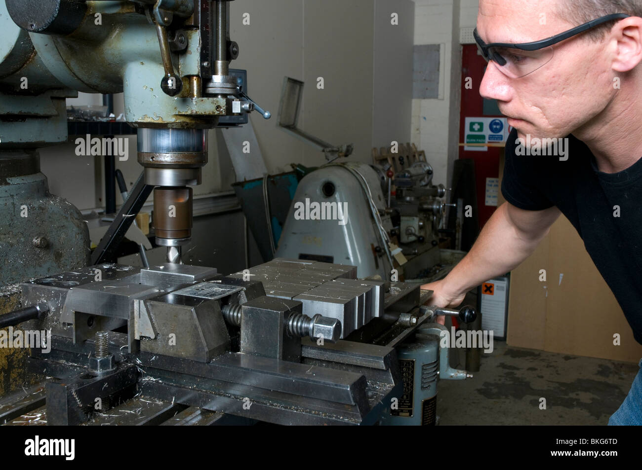 A precision engineer in his using a milling machine wearing