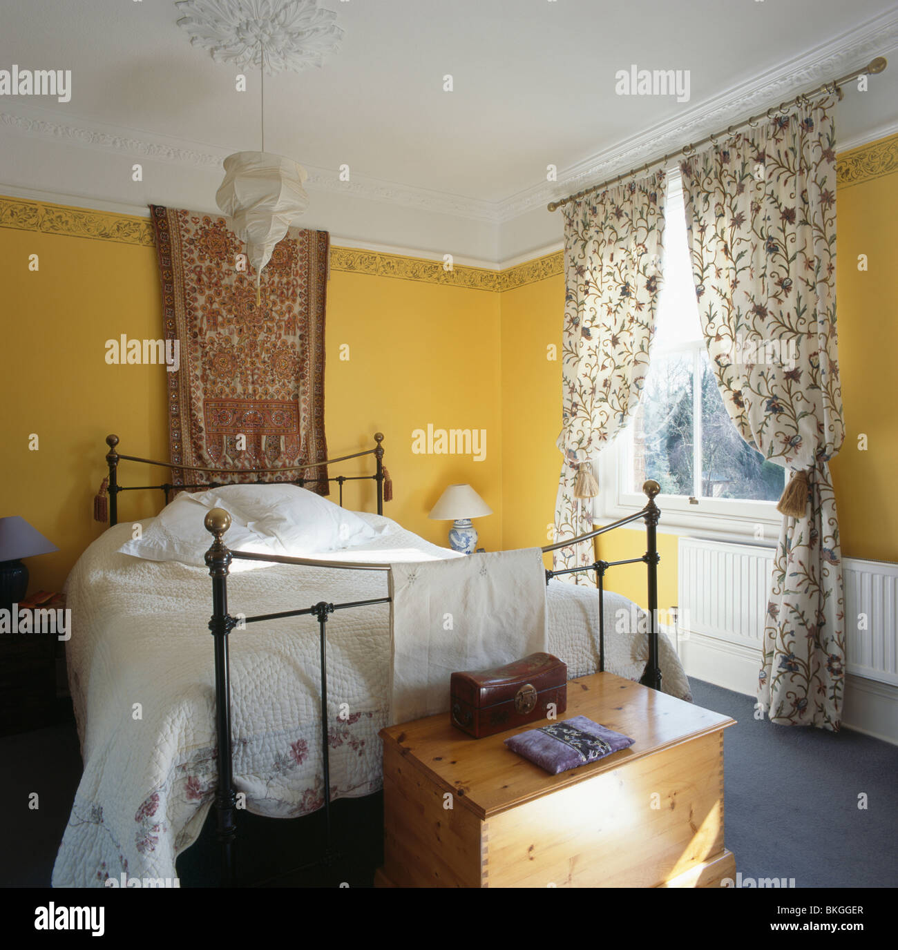 Fabric On Wall Above Brass And Iron Bed With White Bed Cover