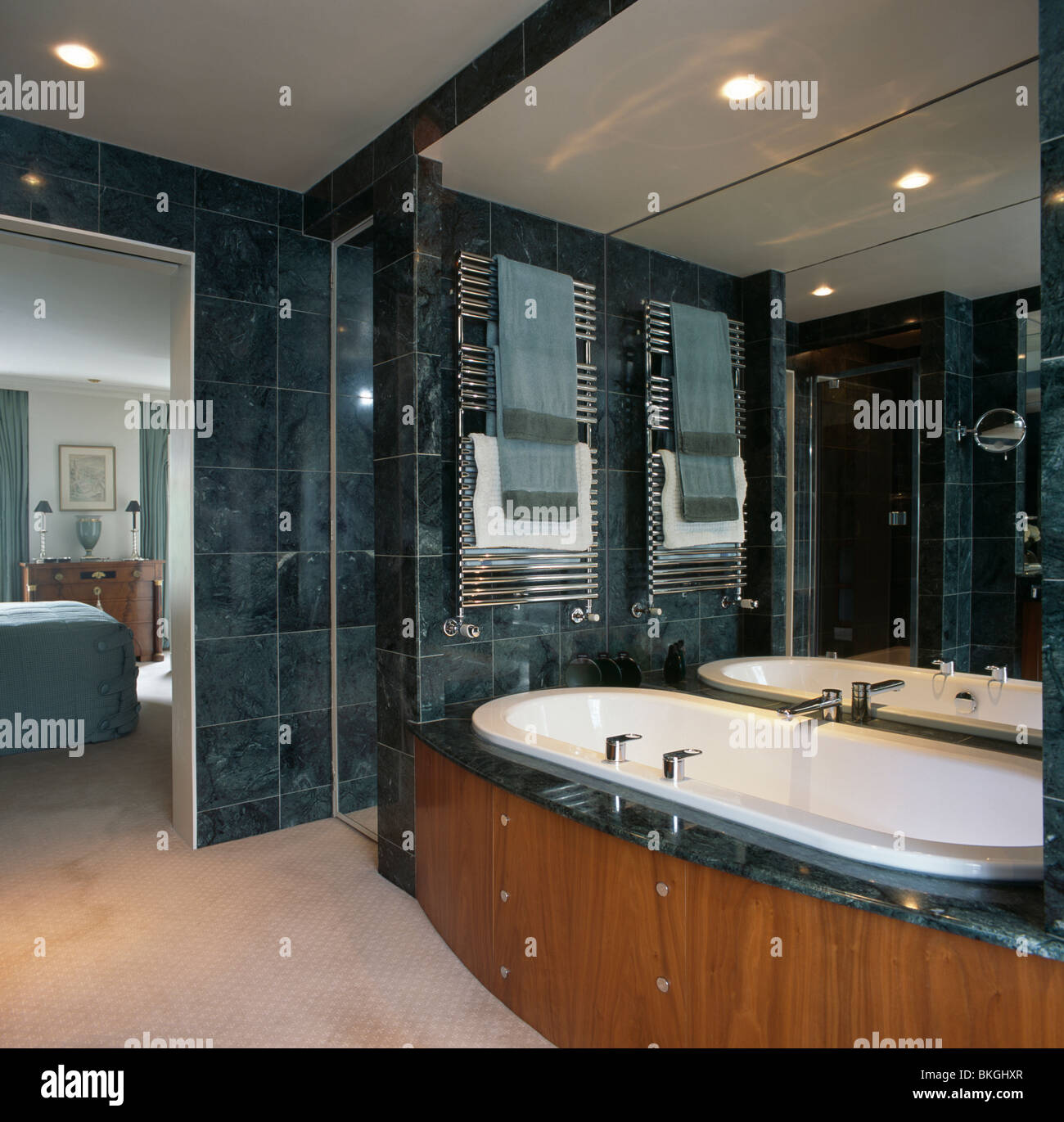 https://c8.alamy.com/comp/BKGHXR/towels-on-heated-towel-rails-above-bath-in-modern-marble-tiled-en-BKGHXR.jpg