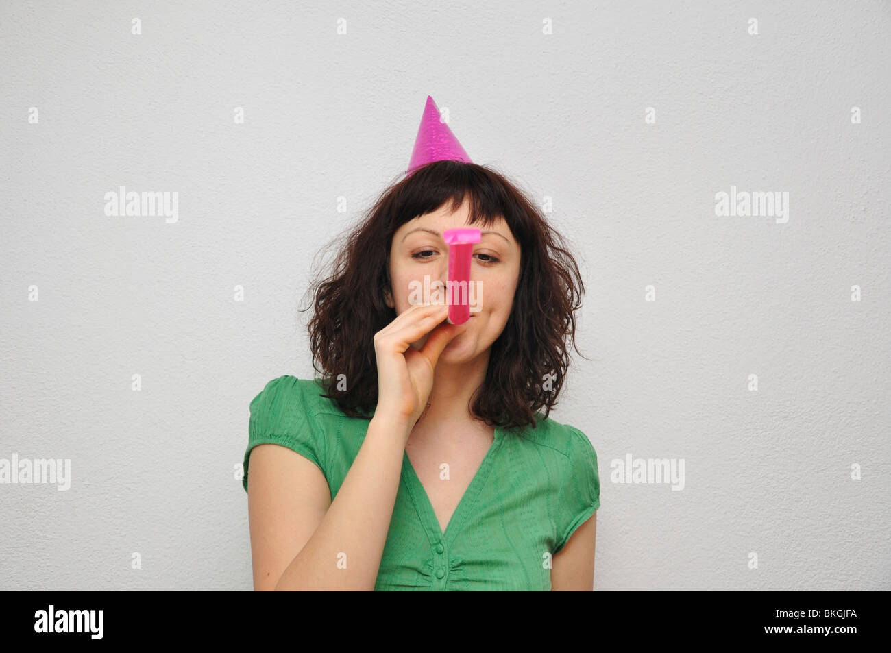 Young woman blowing noise blower Stock Photo - Alamy