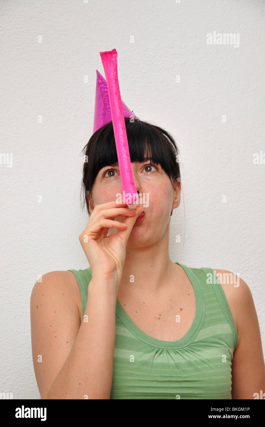 Young woman blowing noise blower Stock Photo - Alamy