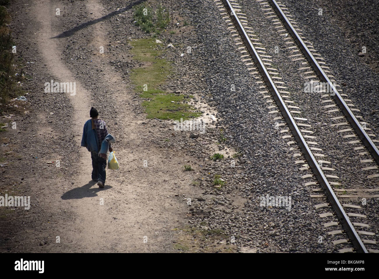 An undocumented Central American migrant traveling to work in the United States waits along the railroad tracks in Mexico City. Stock Photo