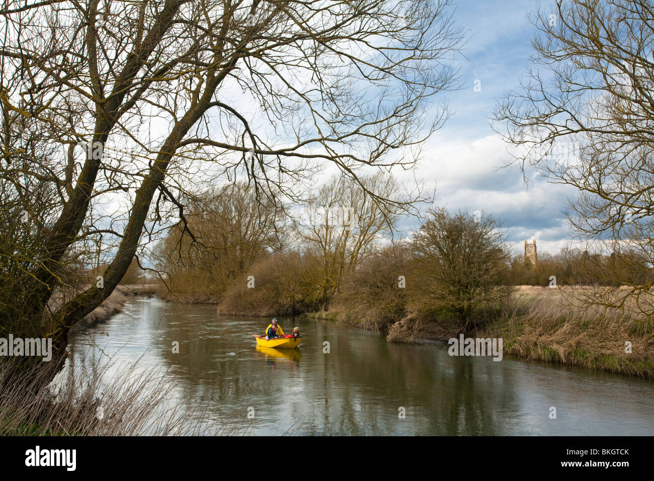 A small boat on the upper reaches of the River Thames in The Cotwolds looking across to St Mary Church in Kempsford, Gloucesters Stock Photo