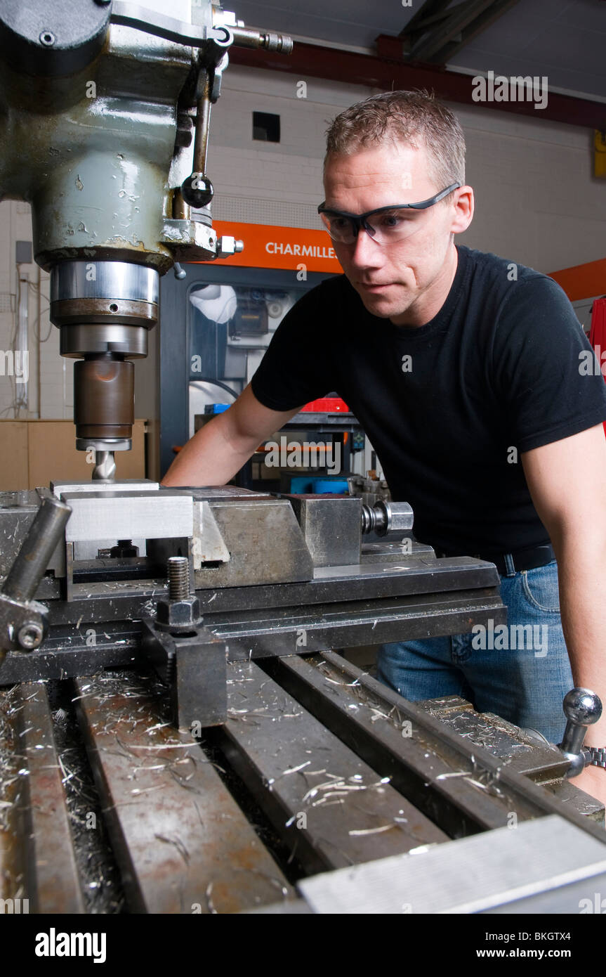 A precision engineer in his using a milling machine wearing