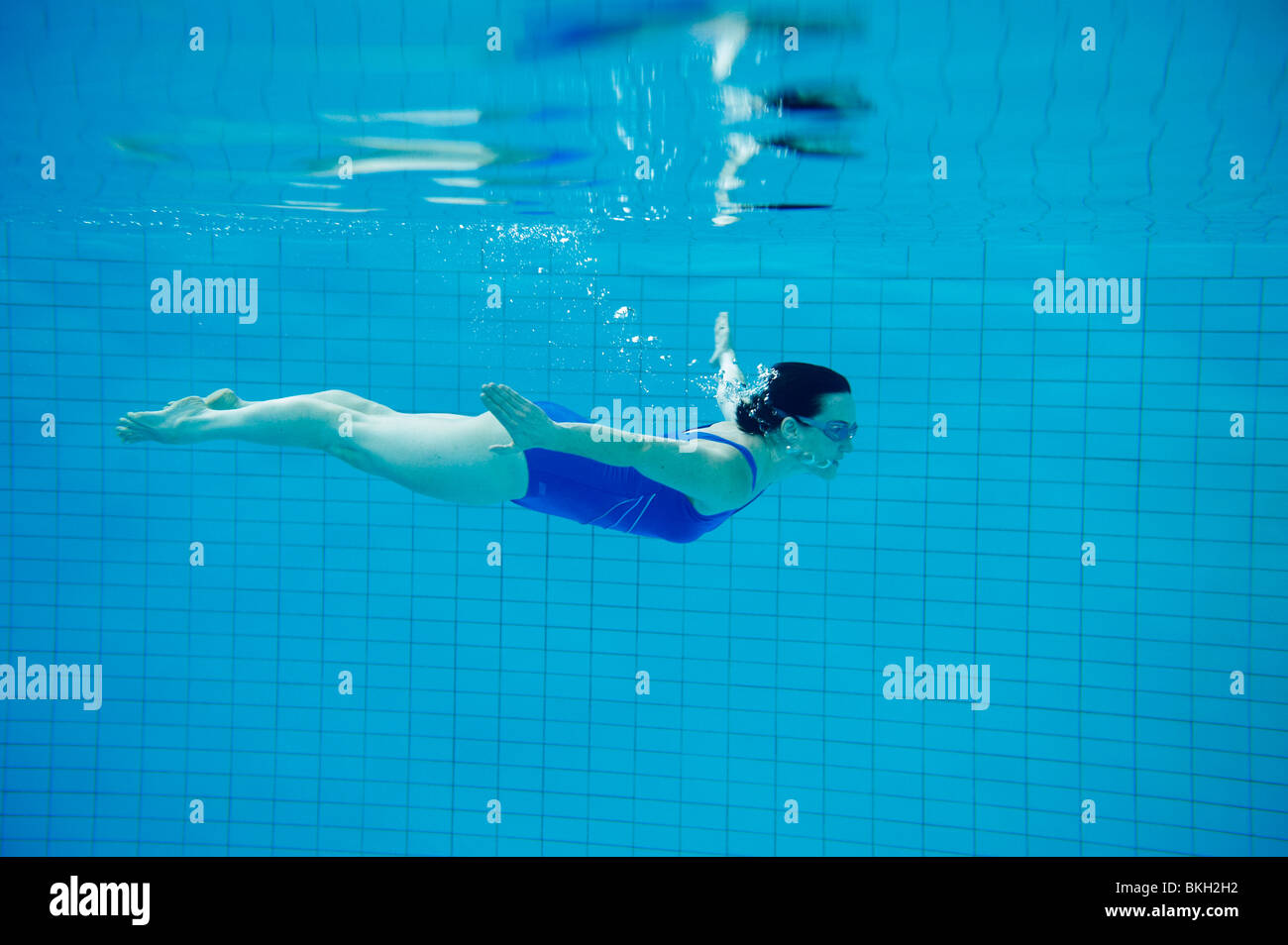 Woman in blue swimming costume swimming under water in pool Stock Photo ...