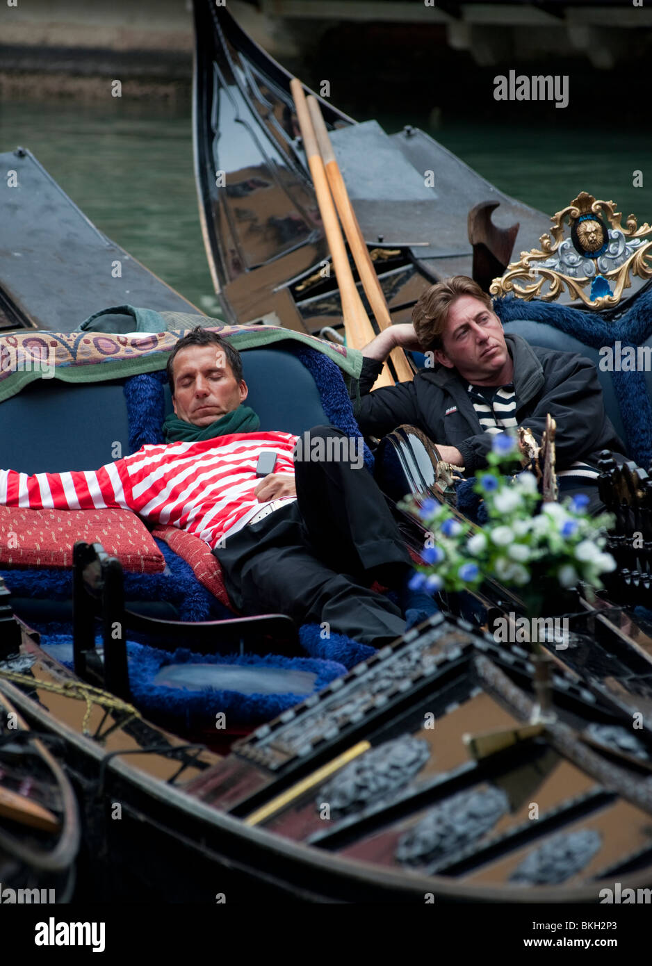 Gondoliers resting in their gondolas on a canal in Venice Italy Stock Photo