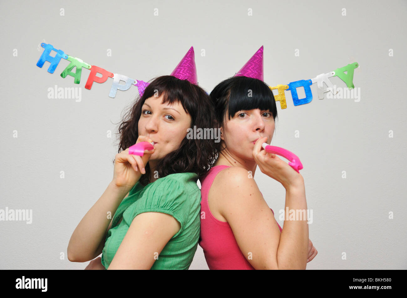 Two young woman blowing noise blower Stock Photo - Alamy