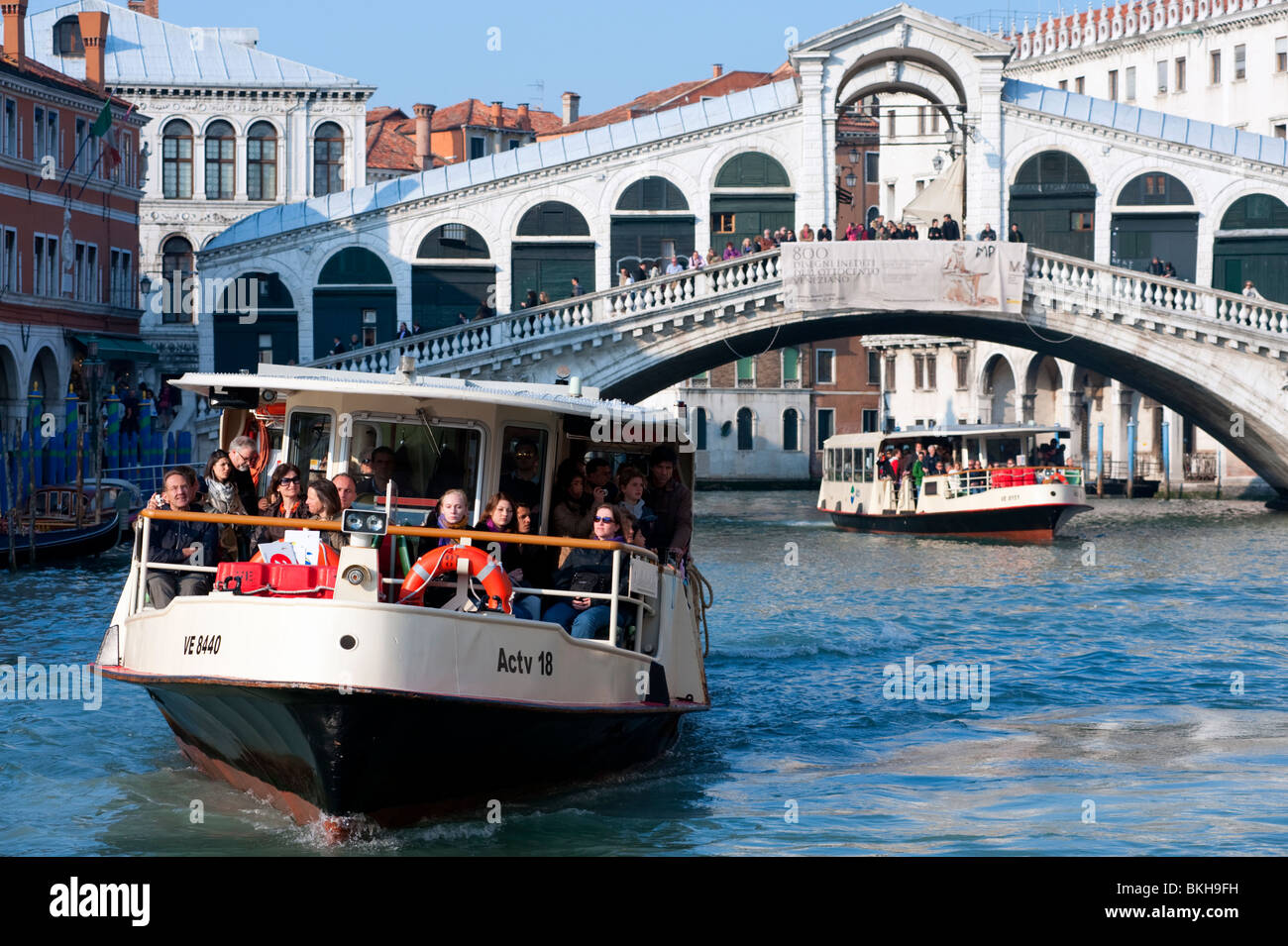 Waterbuses or Vaporetti travelling on the Grand Canal beneath the famous Rialto Bridge in Venice Italy Stock Photo