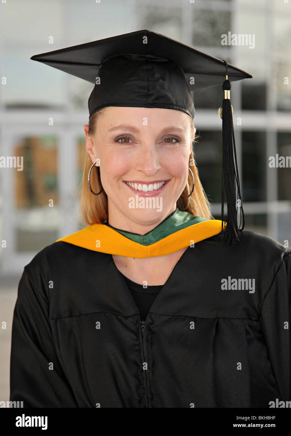 closeup of pretty blond female graduate woman in cap and gown in front