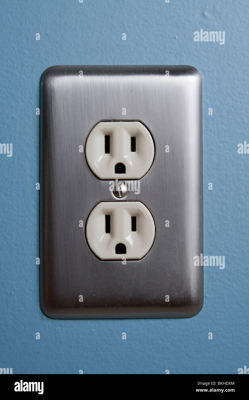 A North American electrical outlet with a stainless steel plate on a blue wall. Stock Photo