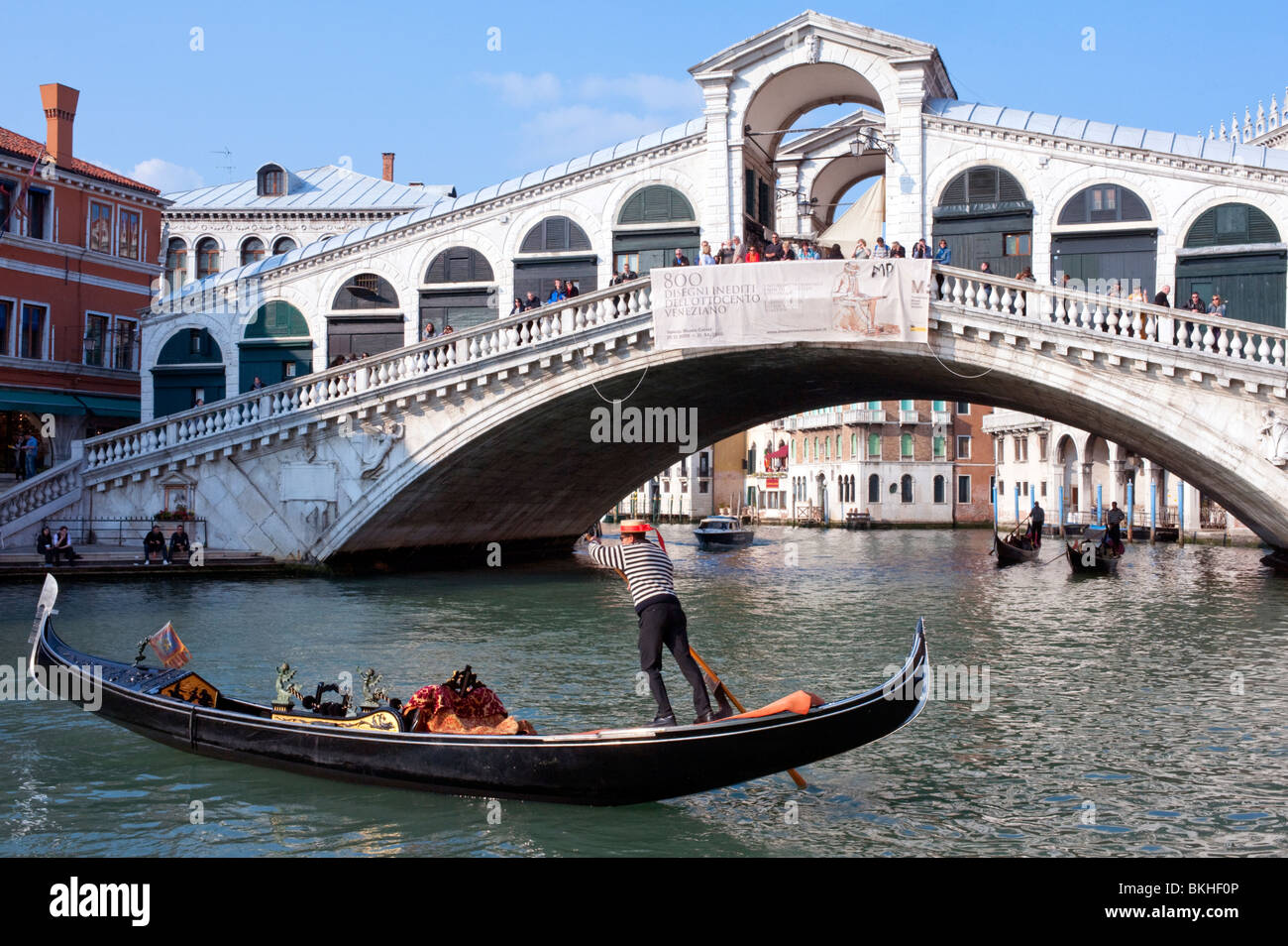 Gondolier and his gondola on the Grand Canal at Rialto Bridge in Venice Italy Stock Photo