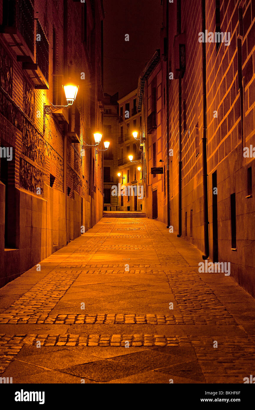 Narrow alley illuminated by street lamps at night, Madrid, Spain Stock Photo