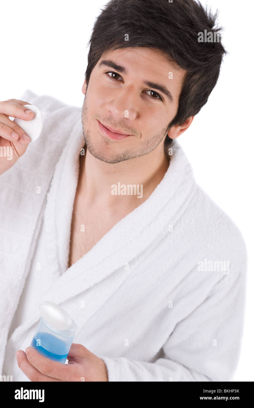 Facial care - Young man cleaning face with lotion on white background Stock Photo