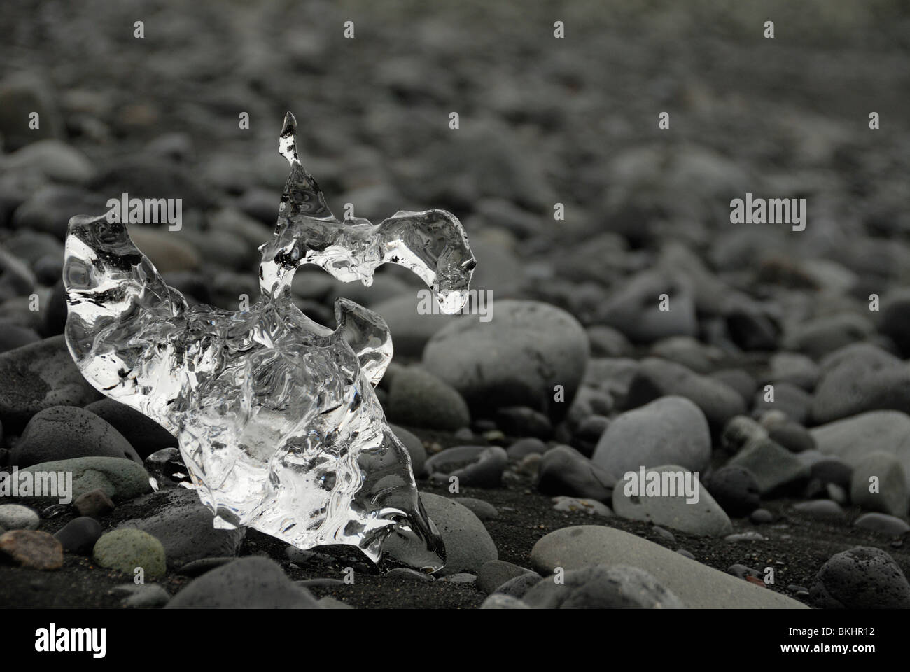 Glass-like Ice-lump on black lava beach Stock Photo