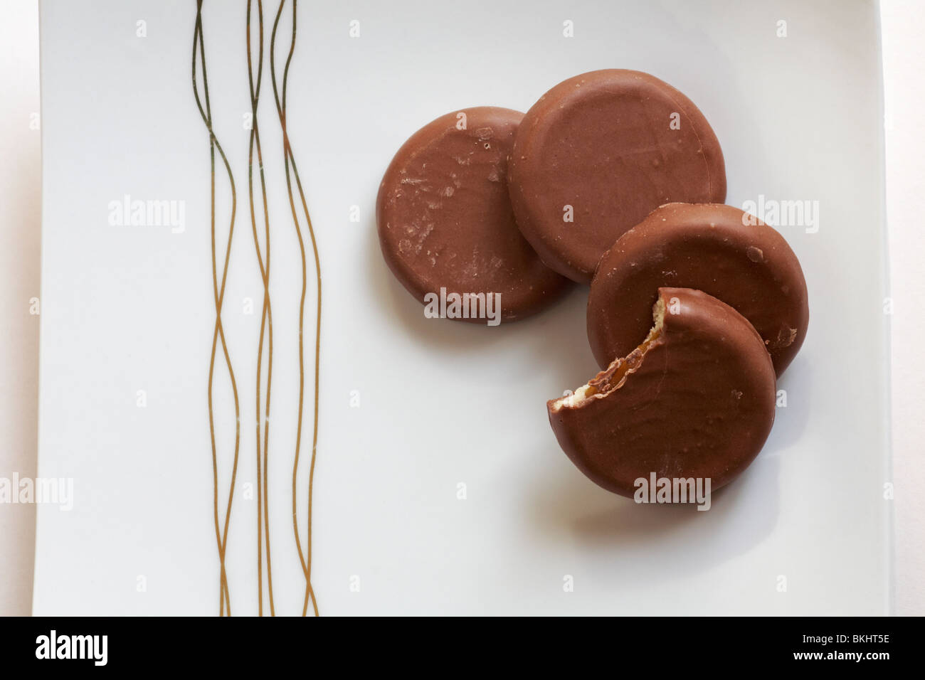 Four Cadbury Caramel biscuits, one bitten into, on plate Stock Photo