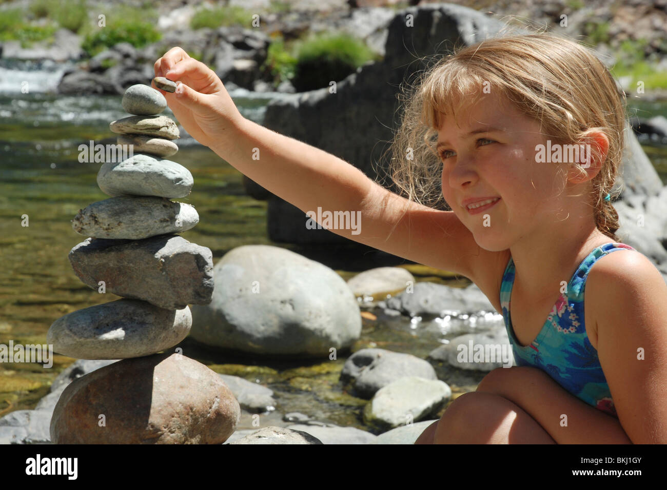 Six year old girl balances rock on top of rock sculpture Yuba River ...