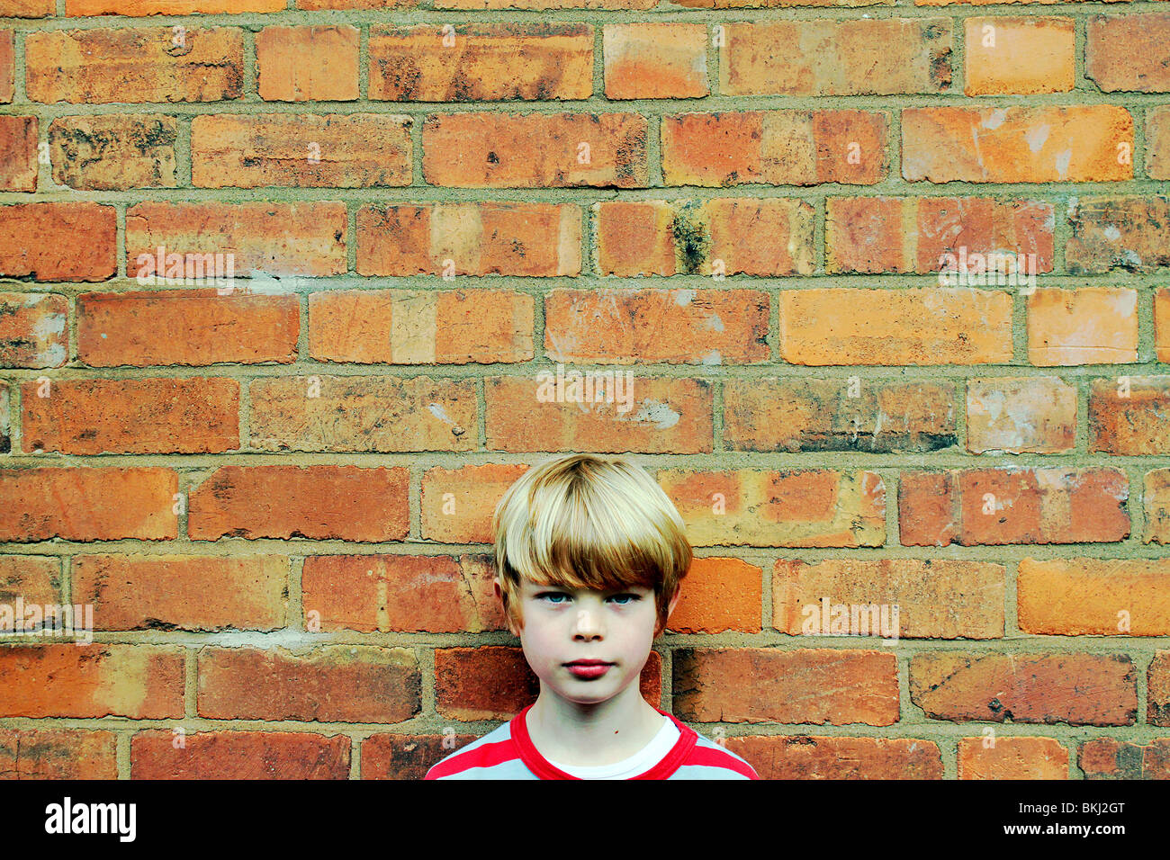 8 year old boy against brick wall Stock Photo