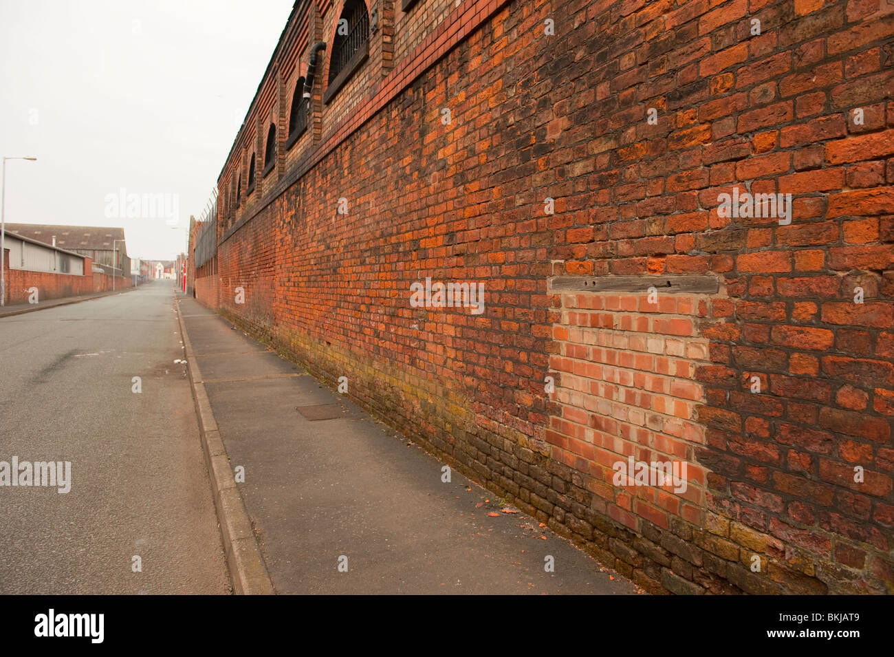 Long blank brick wall fading to vanishing point in distance Stock Photo