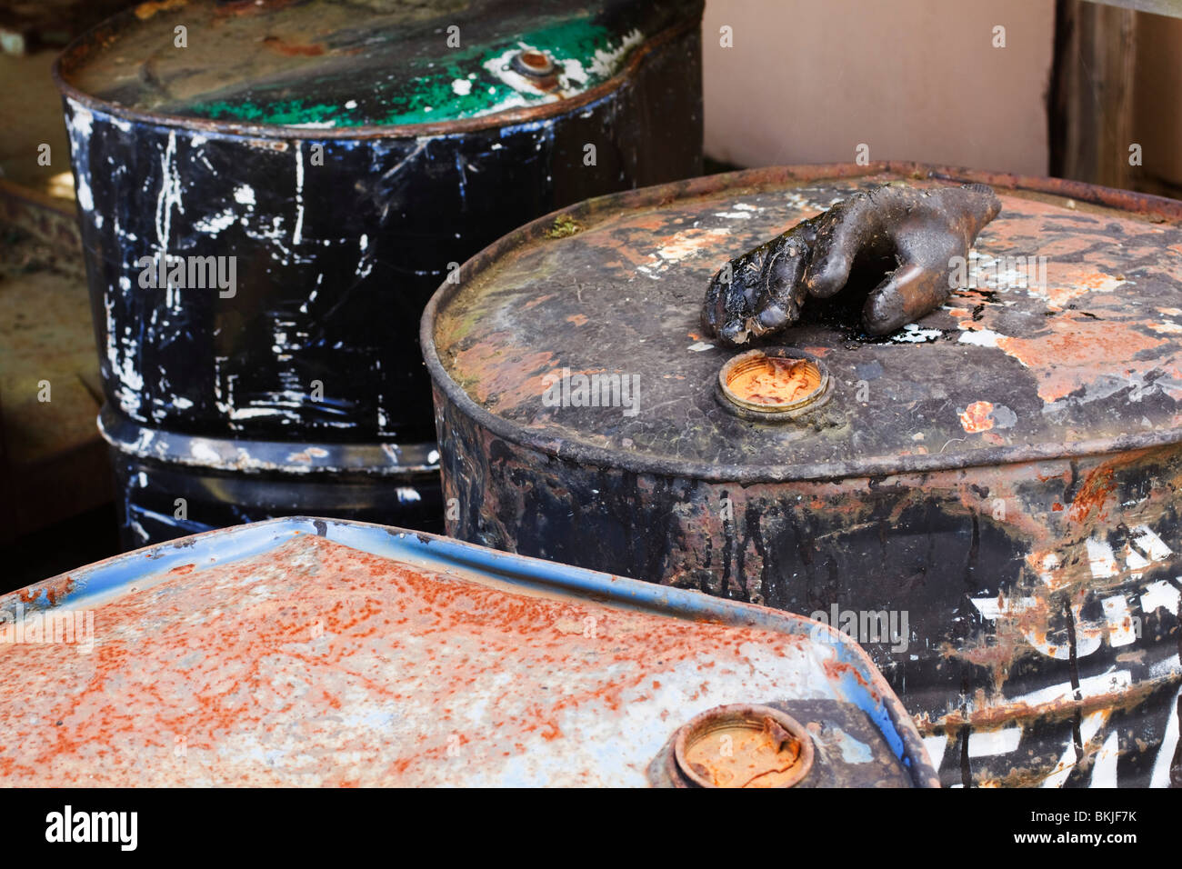 Large drums of creosote with rubber glove caked in creosote. Stock Photo