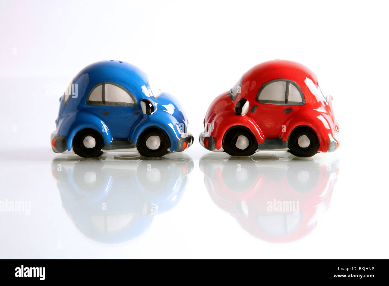 A photograph of a salt and pepper pot shaped as cars, vaguely in the shape of Volkswagen Beetles. Photographed side on. Stock Photo