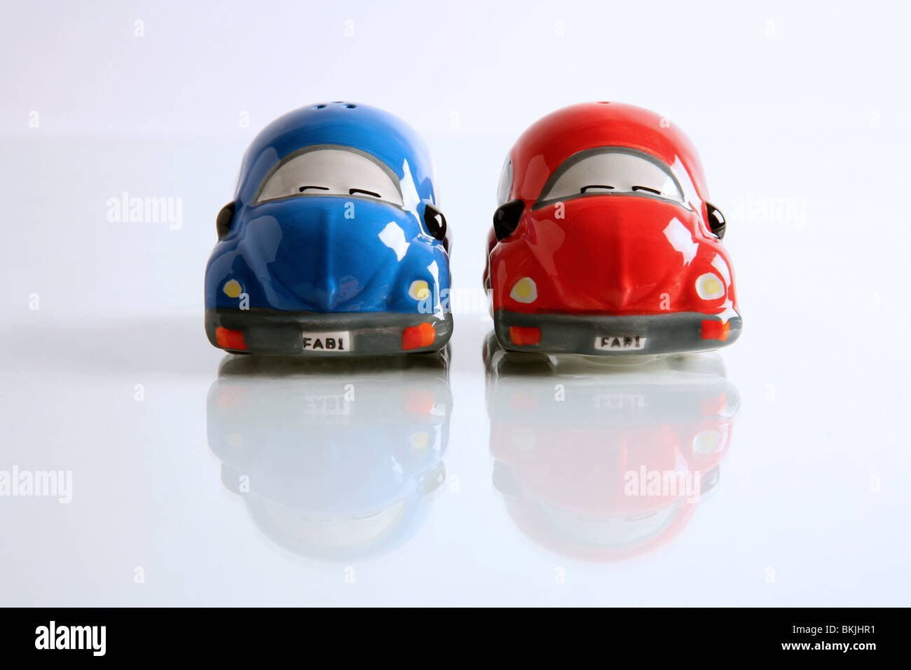 A photograph of a salt and pepper pot shaped as cars, vaguely in the shape of Volkswagen Beetles. Photographed head on. Stock Photo