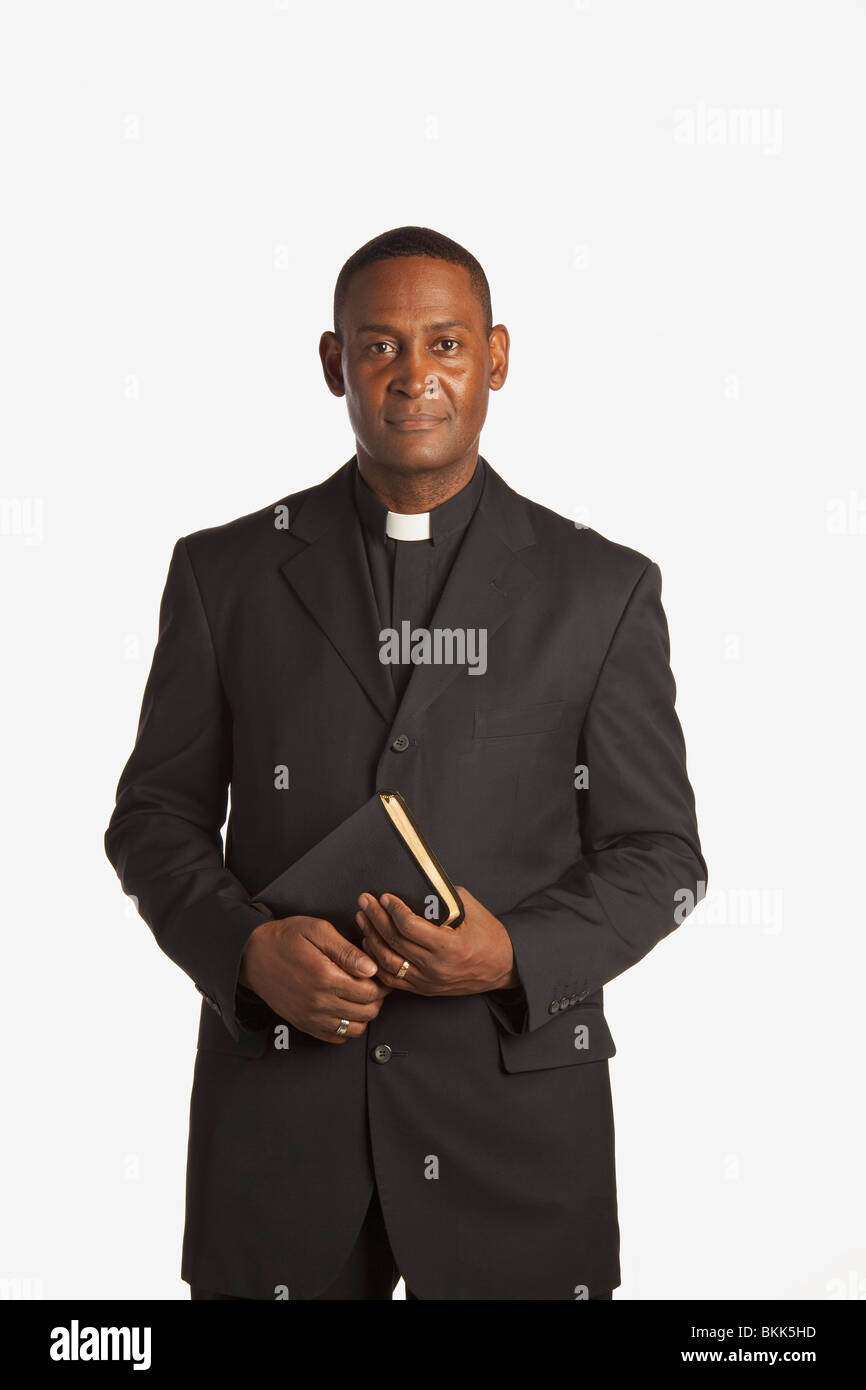 A Man Wearing A White Clerical Collar Holding A Bible Stock Photo