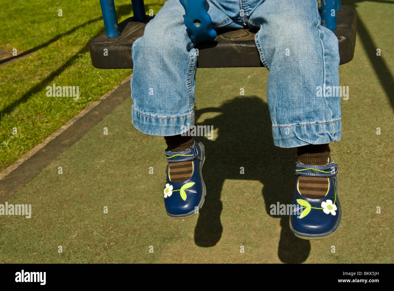 Child's legs hanging down from child's playground swing Stock Photo Alamy