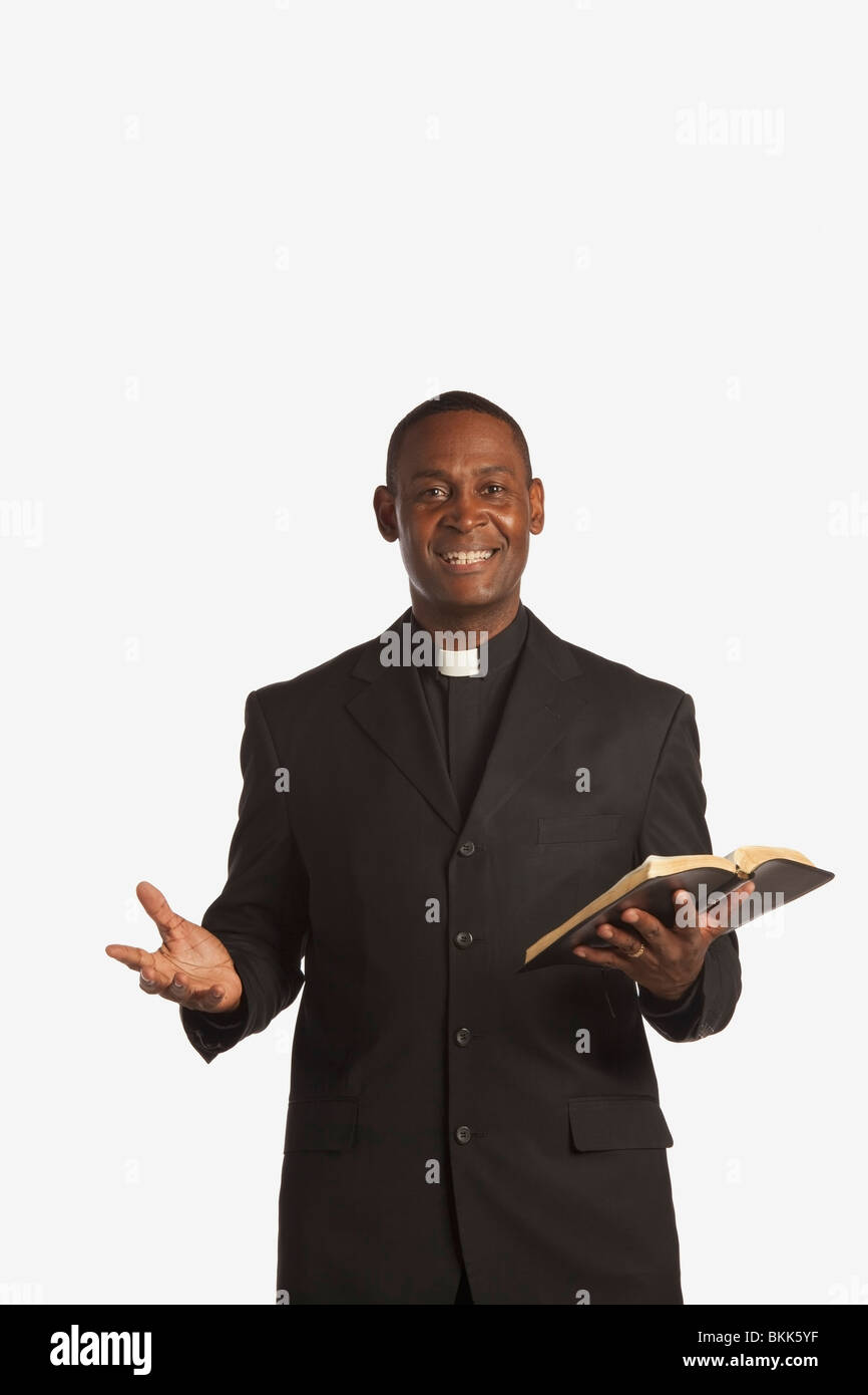 A Man Wearing A Clerical Collar And Holding A Bible Stock Photo