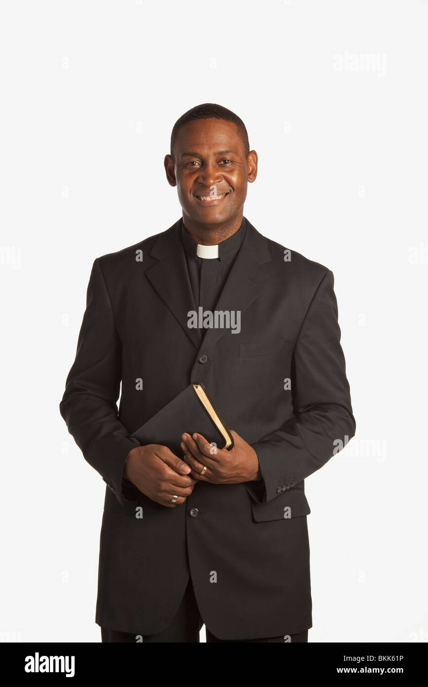 A Man Wearing A Clerical Collar And Holding A Bible Stock Photo