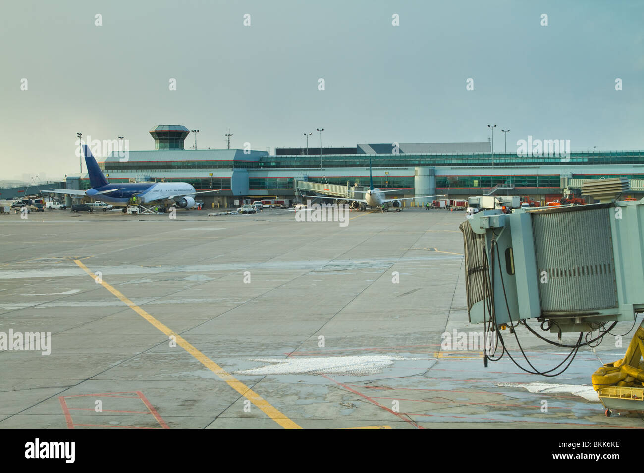 The tarmac at an airport, showing the rear of a passenger plane in the background with an empty gate in the foreground. Stock Photo