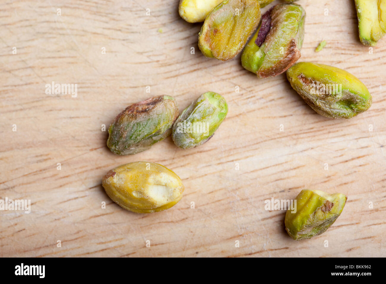 A pile of unshelled pistachio nuts on a wooden board Stock Photo