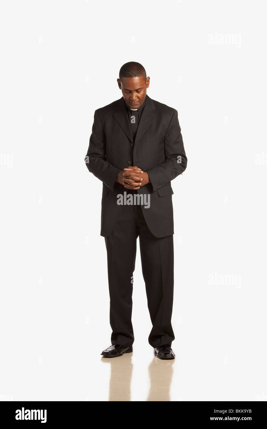 A Man Wearing A Clerical Collar With His Head Bowed In Prayer Stock Photo