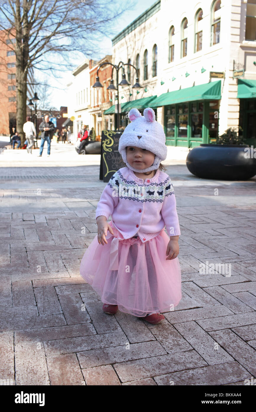 Little girl in a bunny hat and ballerina skirt strolling outside on the downtown mall. Stock Photo