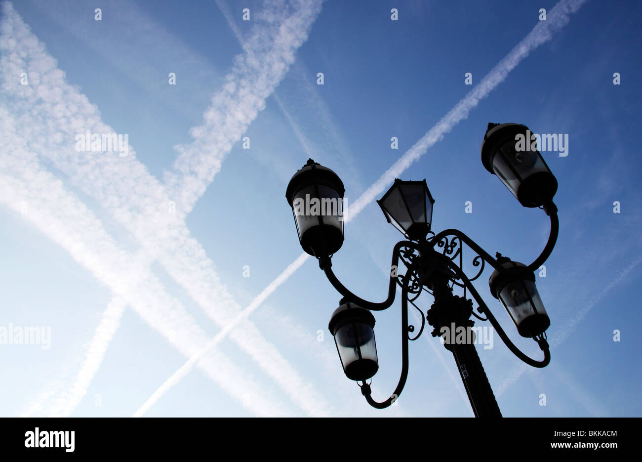 Contrails from jet airliners crossing each other against a blue sky Stock Photo