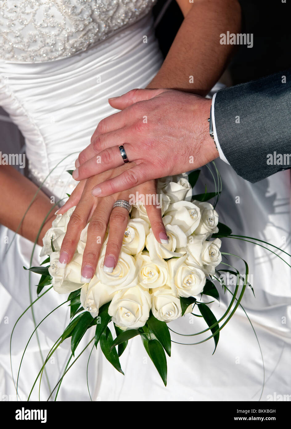Bride and groom holding hands over bridal bouquet Stock Photo - Alamy