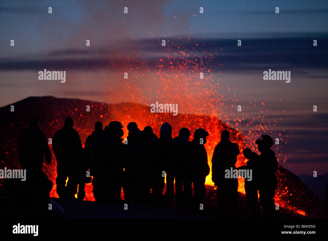 Silhouettes of group of tourists with snow mobiles watching the Iceland 2010 volcanic eruption of the Eyjafjallajökull volcano Stock Photo