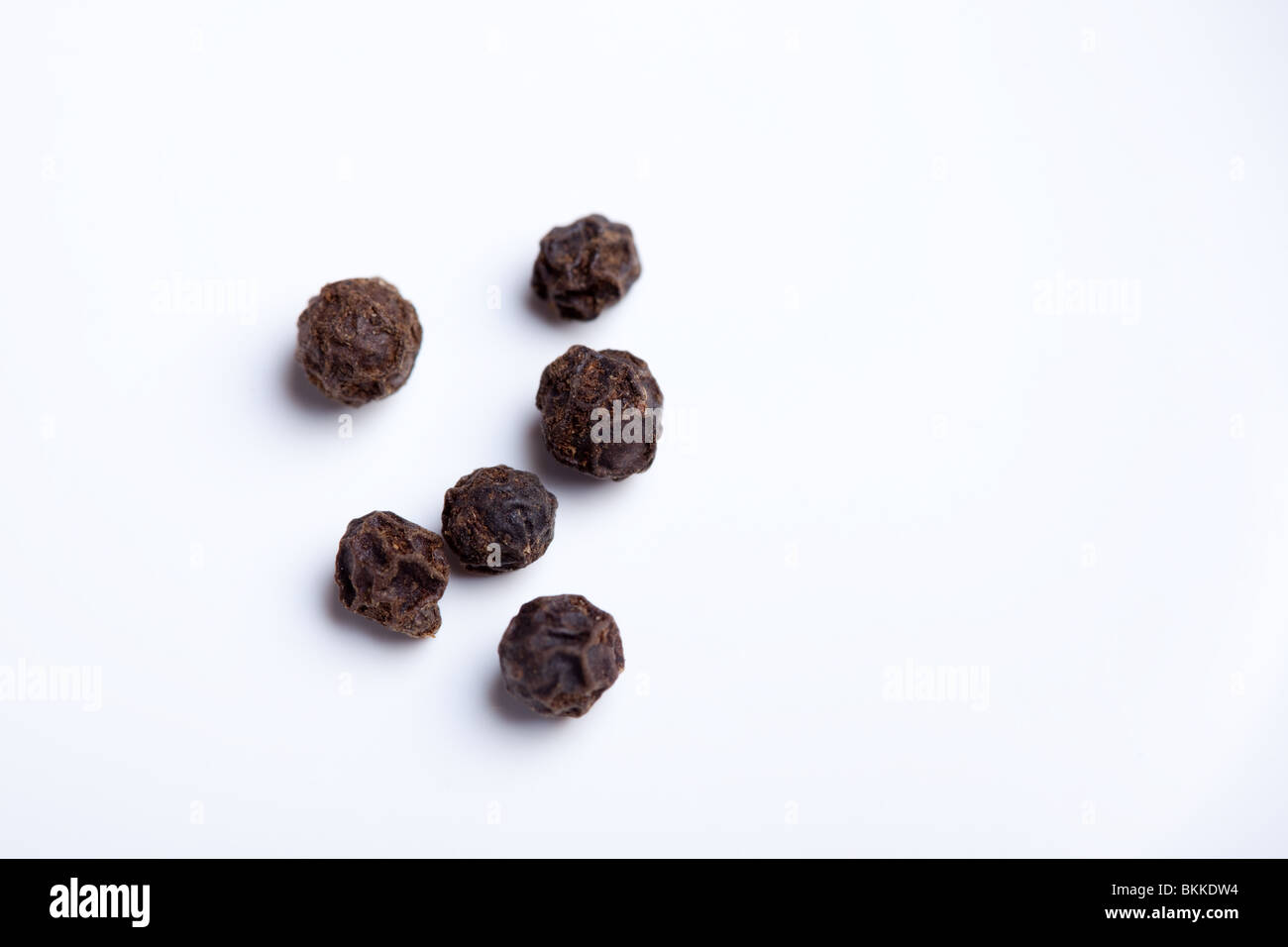 A close up of Black peppercorns (Piper nigrum) on a white plate Stock Photo