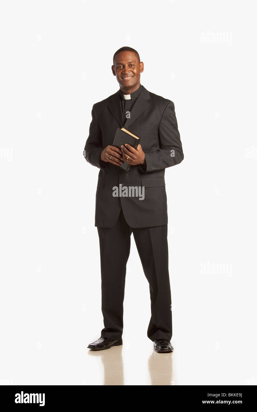 A Man Wearing A Clerical Collar And Holding A Bible Stock Photo