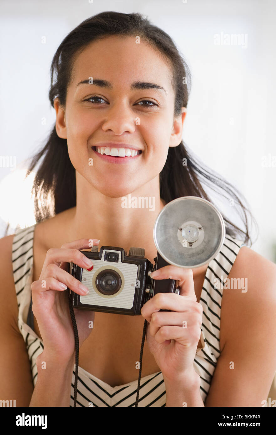 Mixed race woman holding old-fashioned camera Stock Photo