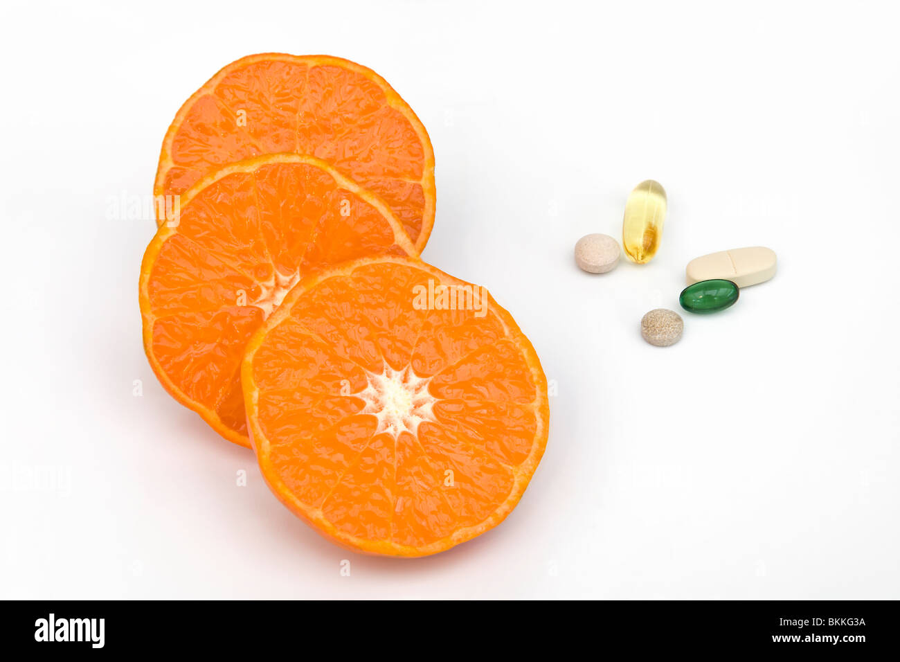Clementine orange halves with a mixture of vitamin tablets which are multi vitamin, peppermint, gingko, ginseng an omega 3 Stock Photo