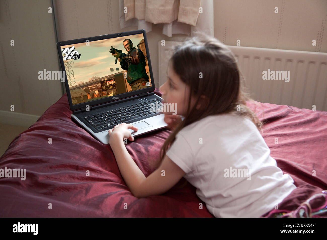 young girl playing the computer game Grand Theft Auto IV in her bedroom Stock Photo