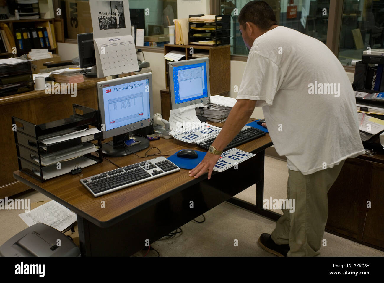 Inmate working at license plate manufacturing computer and printer at ...